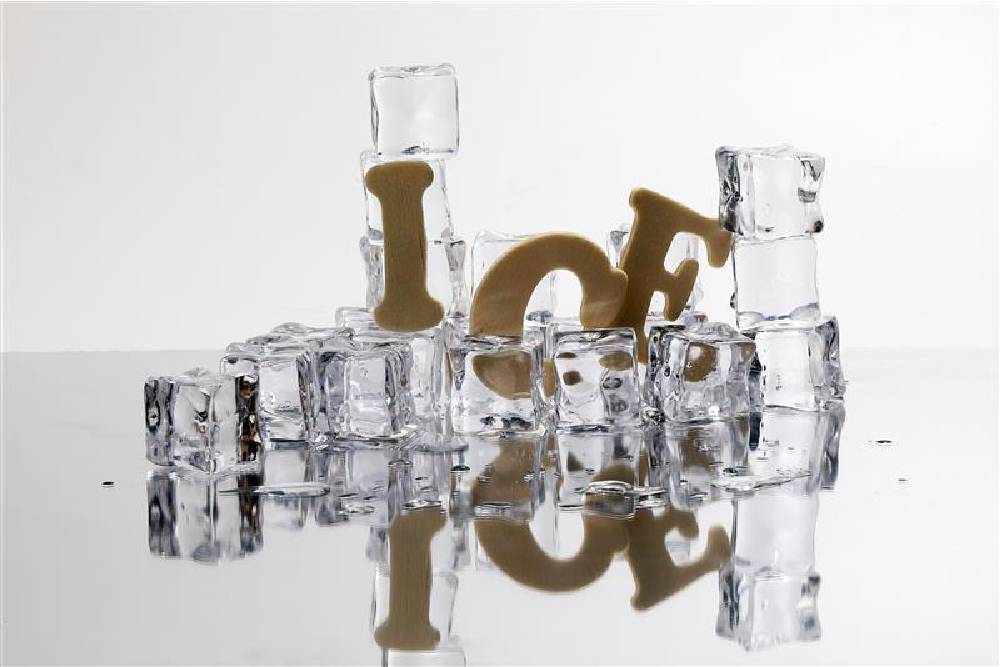 A pile of clear, cubed ice slowly melts, one of the many different types of ice that can affect your beverages. The word “Ice” falls as the pile of cubes melt.