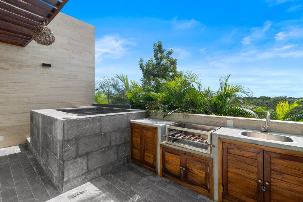 An absolutely gorgeous, tropical rooftop outdoor kitchen with a modern kitchen sink design.