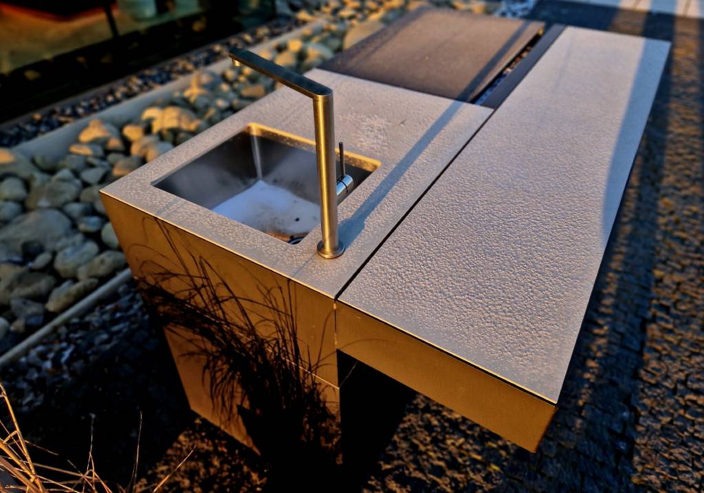 A gorgeous stainless steel outdoor sink installation within a backyard bartop.